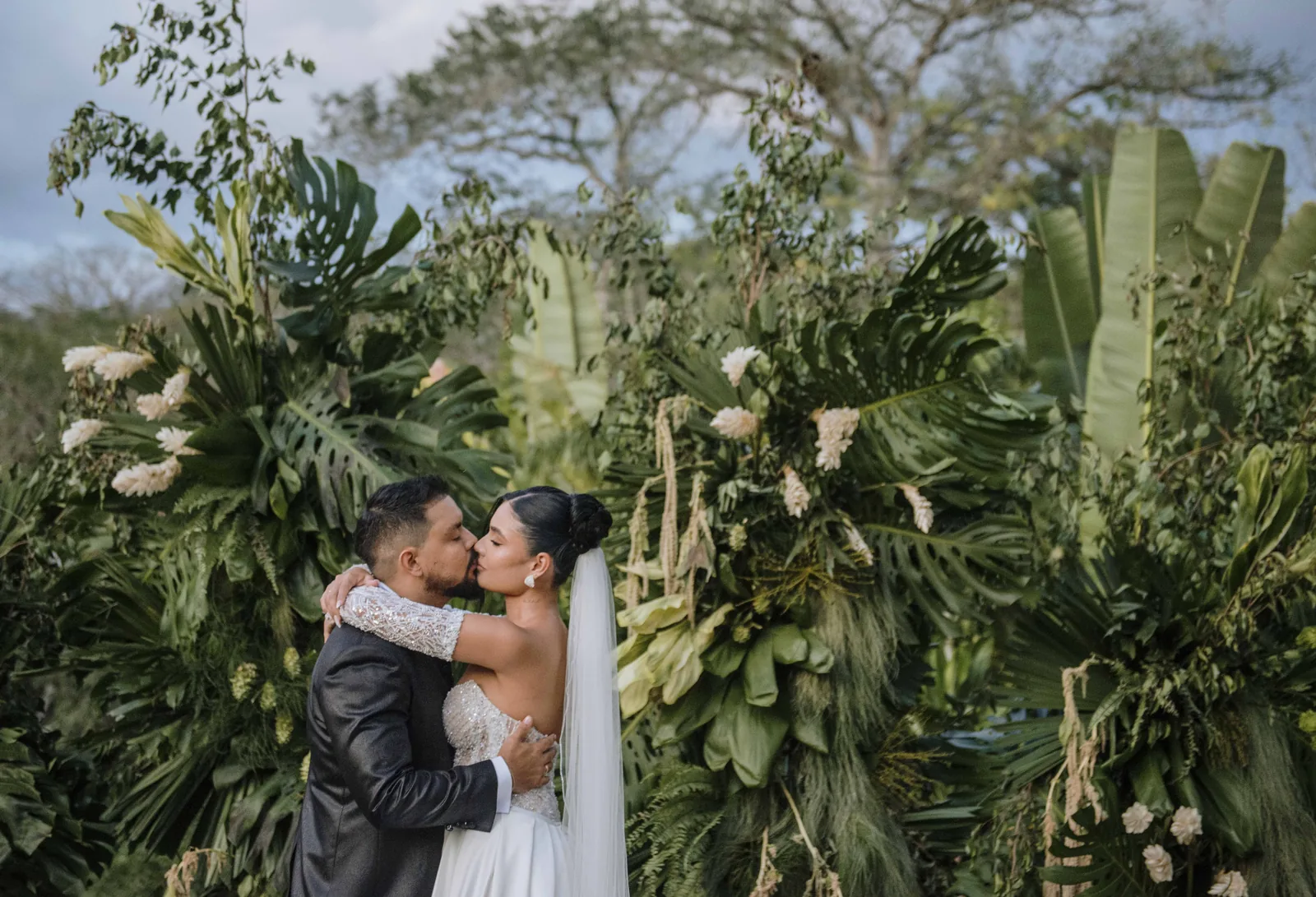 Novios besándose entre jardines tropicales en una boda en Colombia