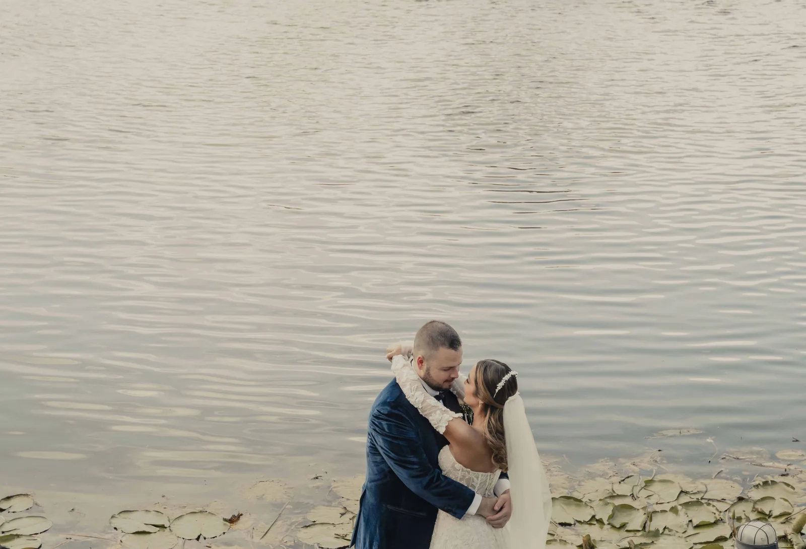 Pareja de novios abrazándose junto al lago